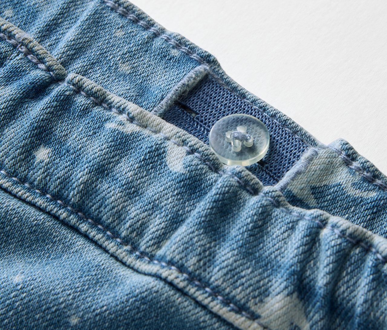 Gros plan sur un tregging pour enfant avec un bouton et un élastique réglable à la taille.