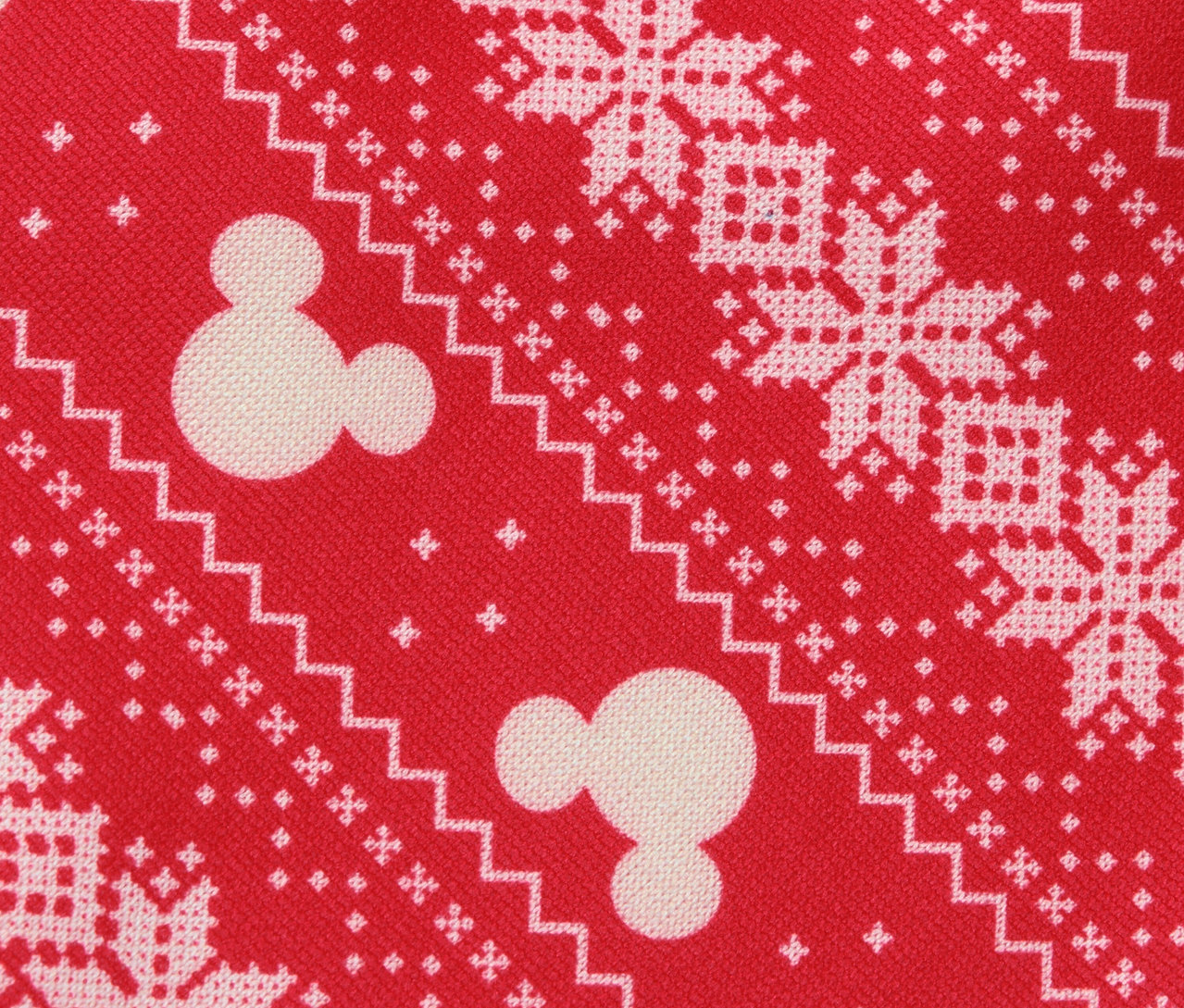 Surface en tissu rouge à motifs avec des flocons de neige blancs et des motifs de Mickey Mouse.