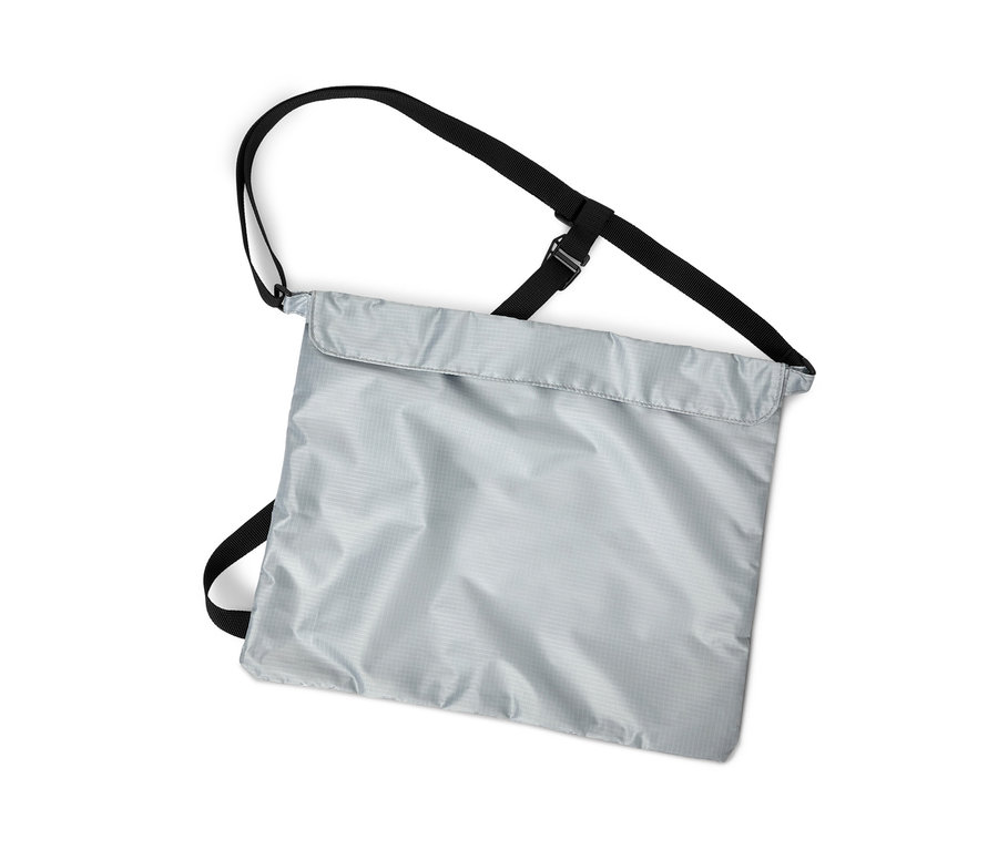 Prise de vue verticale d'un sac à provisions pour vélo argenté avec des sangles noires sur un fond blanc.