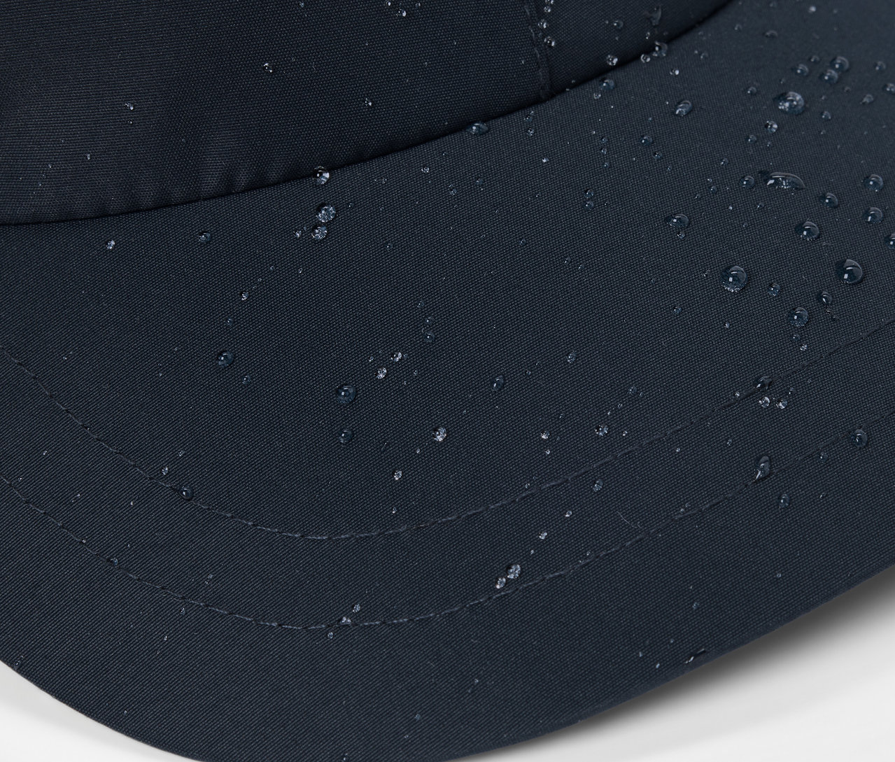 Gros plan d'une casquette polyvalente noire avec des gouttes d'eau à la surface.