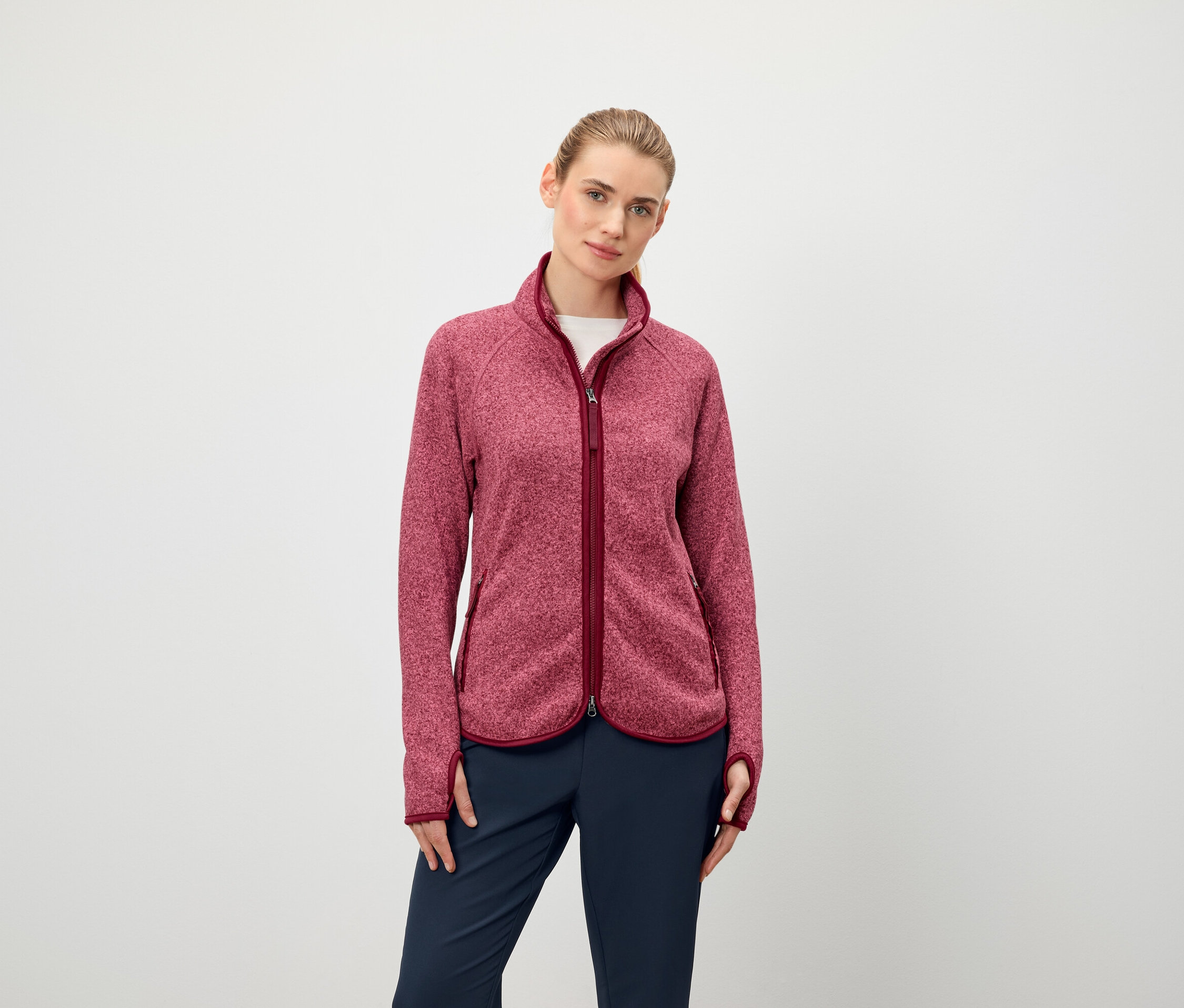 Une femme porte une veste polaire à manches longues avec fermeture éclair et un pantalon bleu foncé.