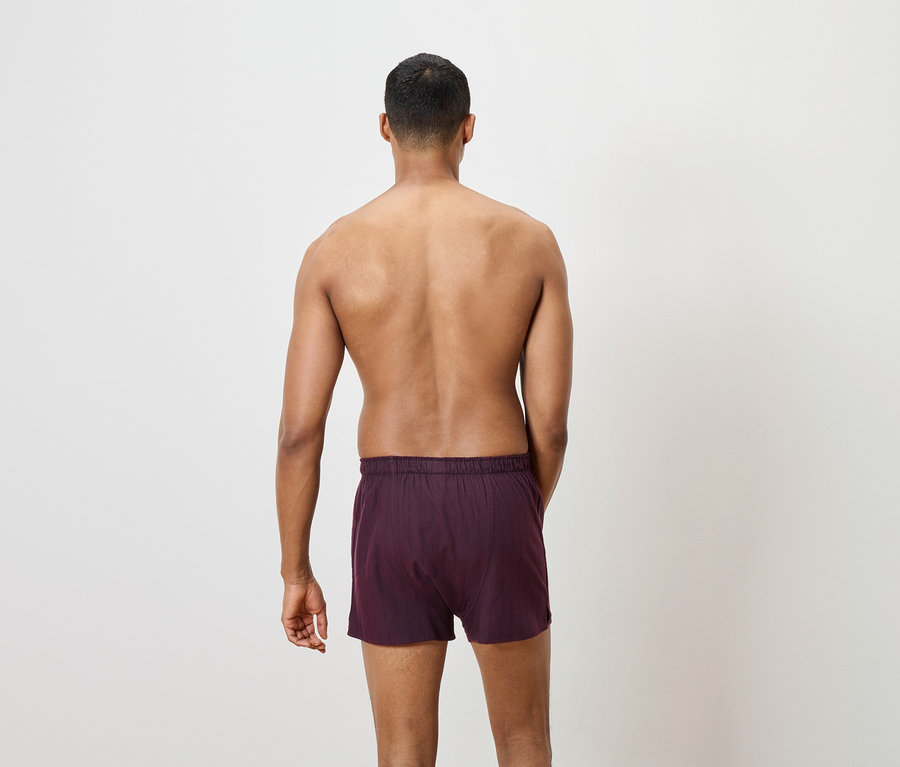 Un homme, vu de dos, porte un caleçon bordeaux.