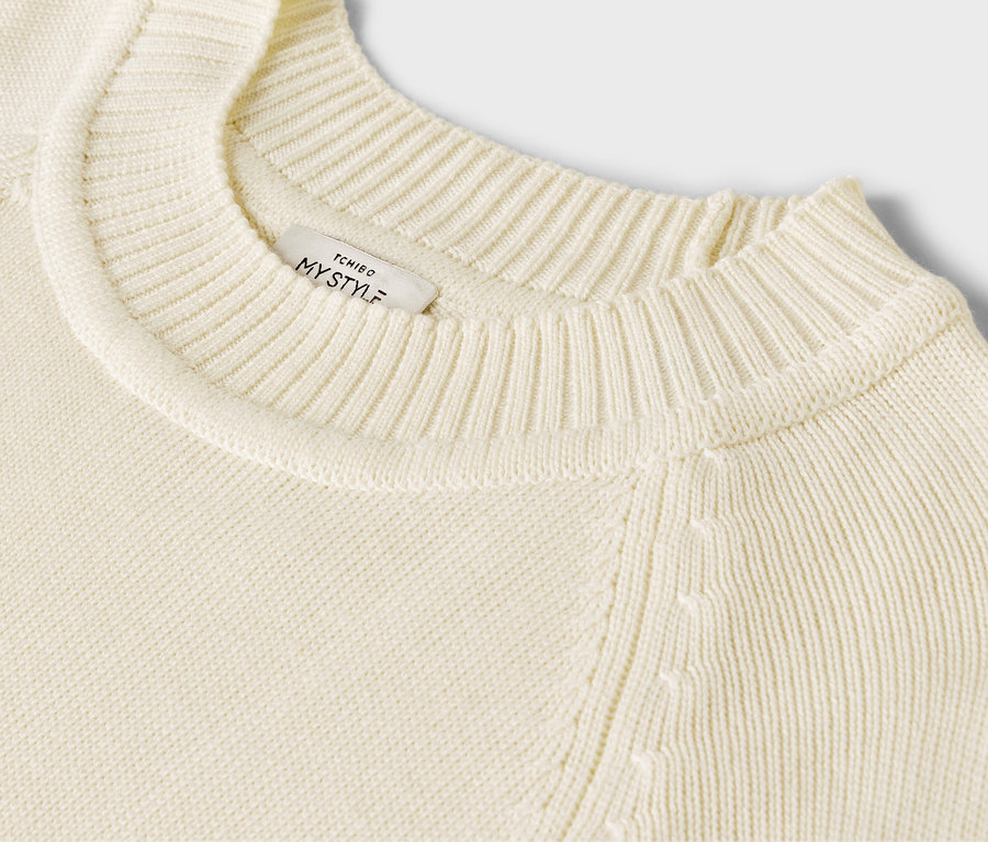 Détail d'un long pull en maille couleur blanc crème.