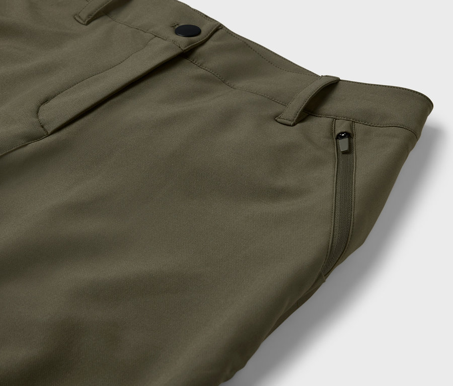 Détail d'un pantalon vert olive avec une poche zippée.
