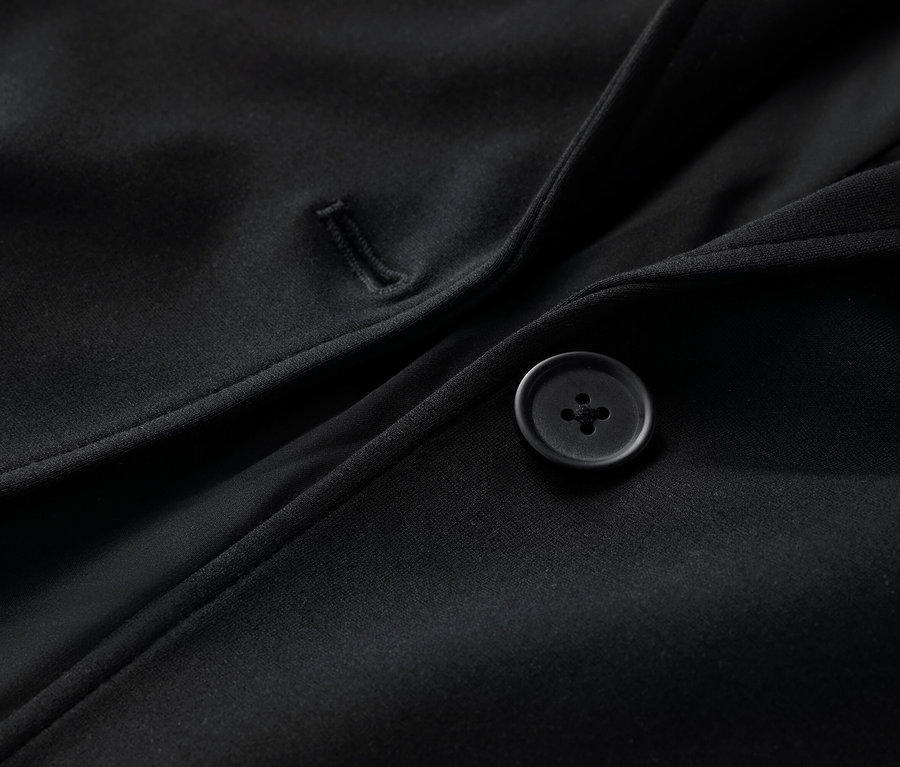 Gros plan sur un blazer en jersey noir avec un bouton.