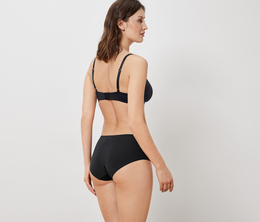 Une femme, vue de dos, porte un soutien-gorge et une culotte noirs.