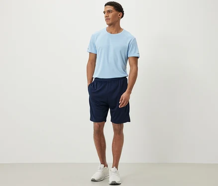 Un homme debout portant un short de sport et un t-shirt.