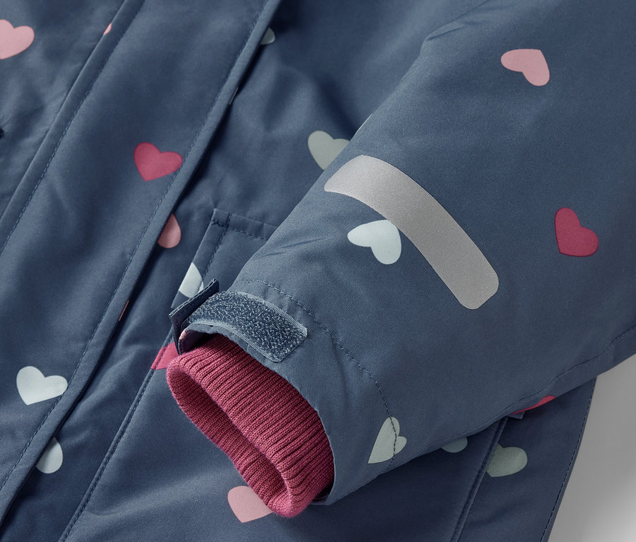 Détail d'une combinaison de ski 2 pièces bleue pour enfants avec des cœurs roses et blancs.