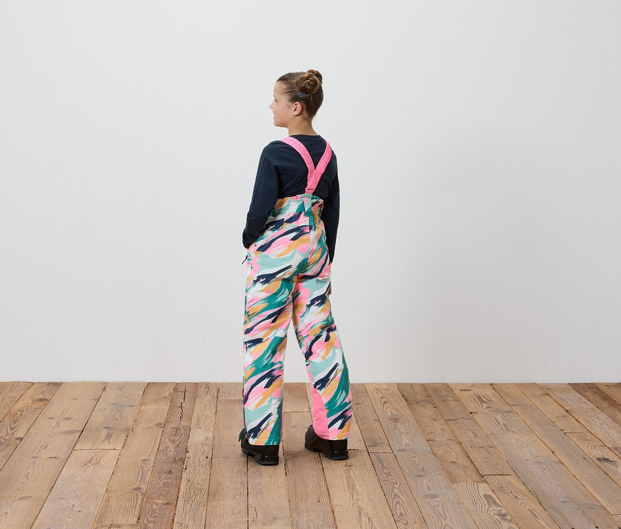 Une fille en salopette à motifs colorés se tient dos à la caméra.