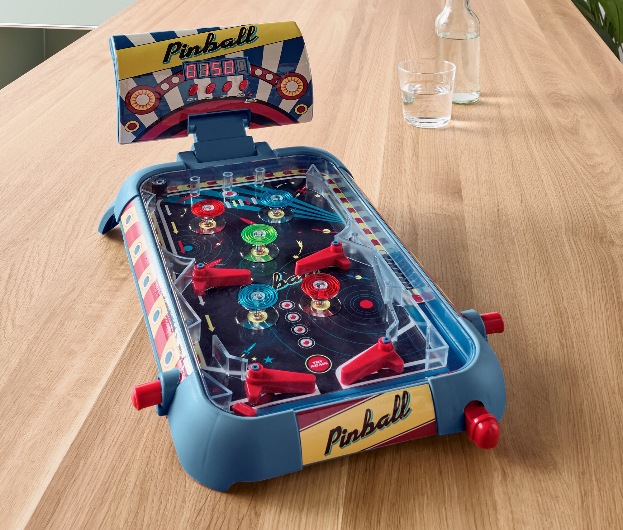 Un mini flipper bleu sur une table en bois.