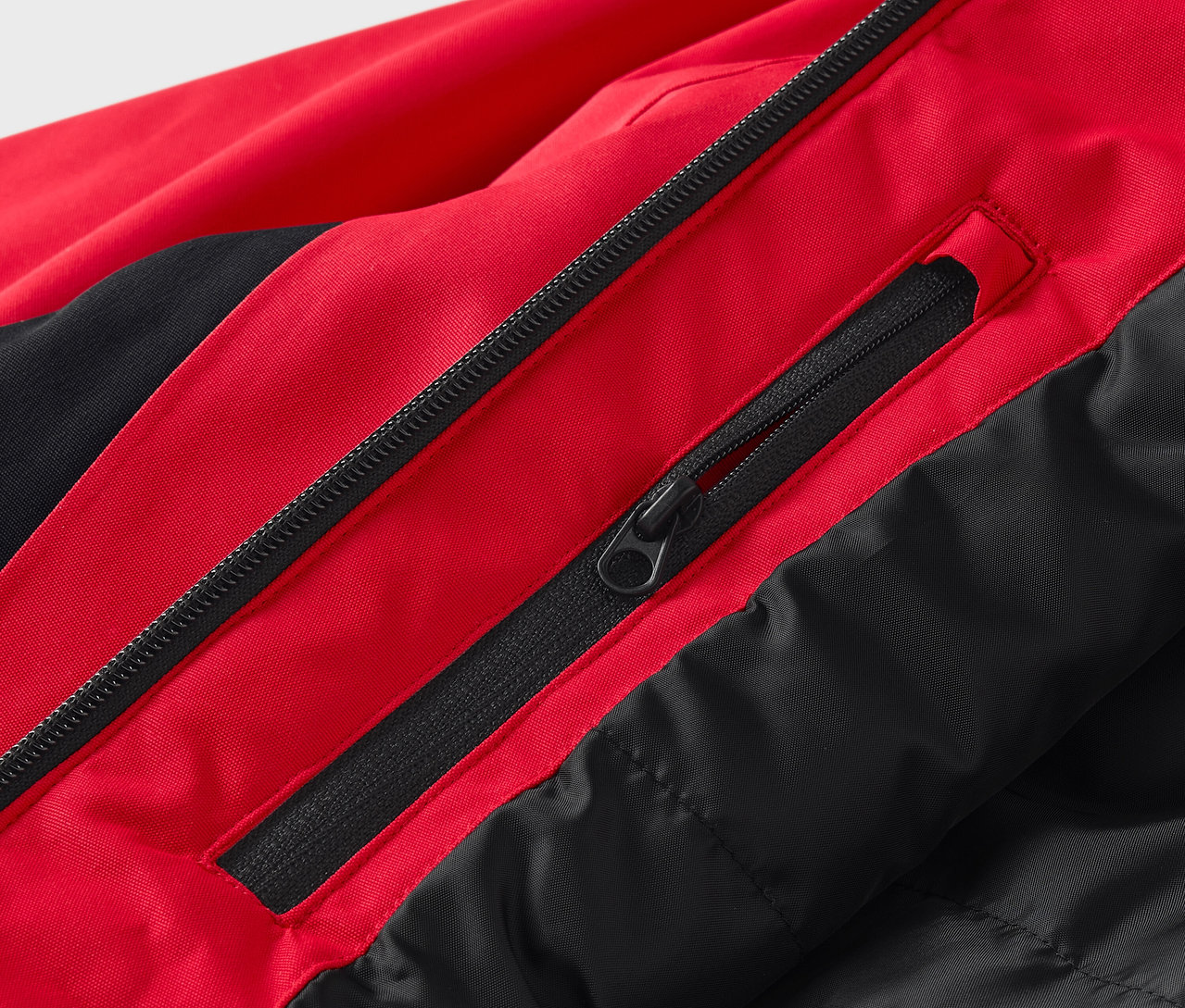 Gros plan sur une veste rouge et noire avec des fermetures éclair.