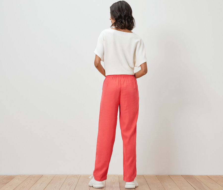 Une femme porte un pantalon tissé et un haut.