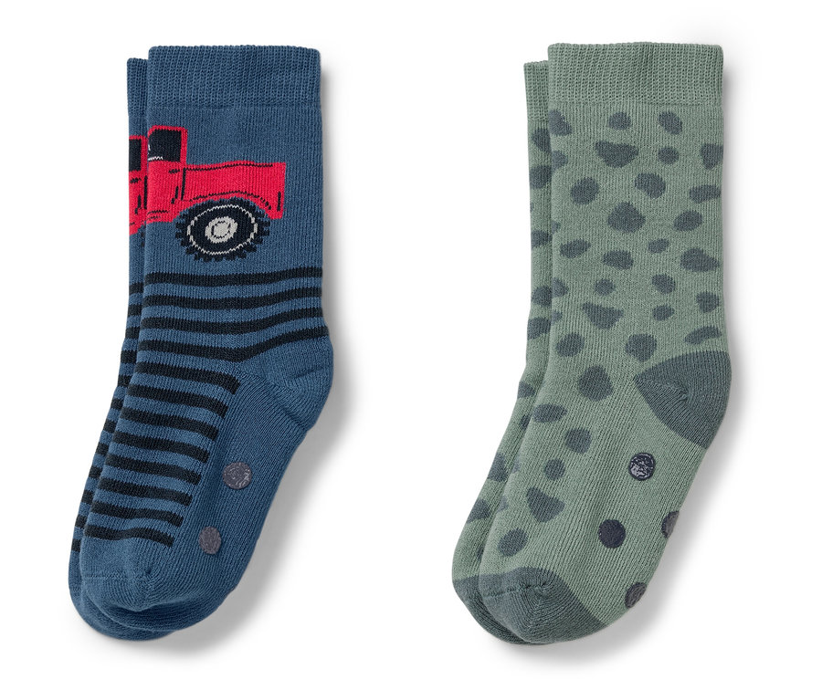 Deux paires de chaussettes. Une bleue avec un camion rouge et des rayures, une verte avec des pois vert foncé.