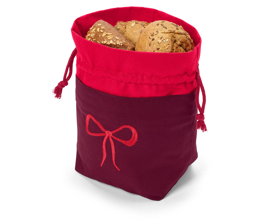 Pain multigrains dans un sac en tissu rouge et bordeaux avec cordon de serrage et broderie de nœud.