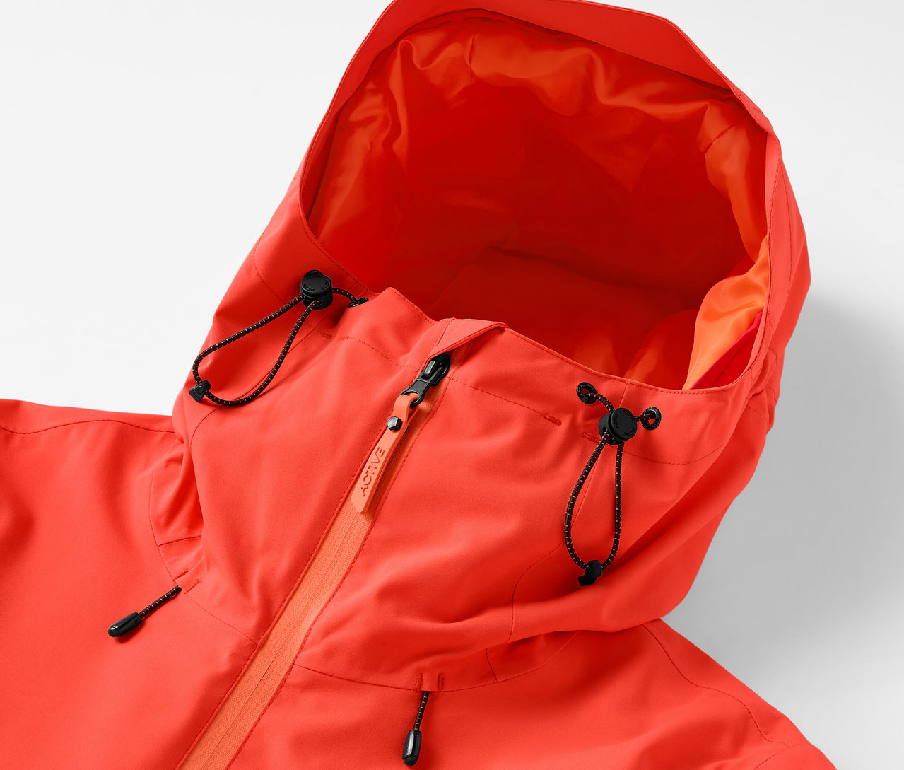 Gros plan d'une veste orange à capuche avec cordon de serrage et fermeture éclair.