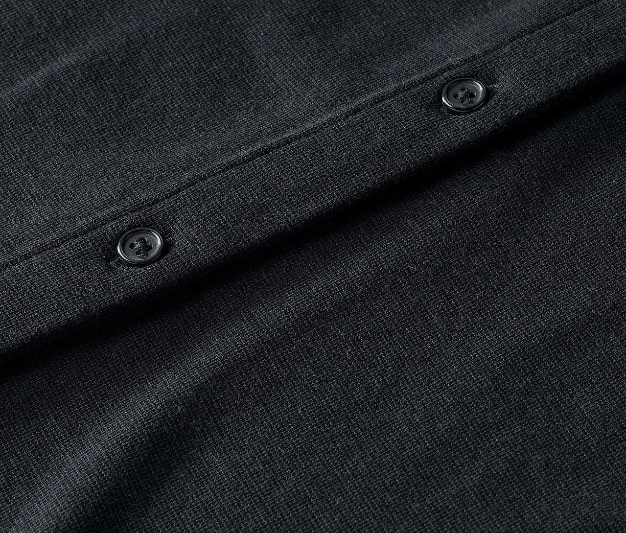 Gros plan sur un cardigan noir avec des boutons.