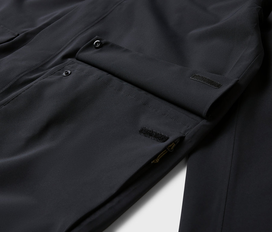 Gros plan sur une veste noire avec des poches et des boutons.