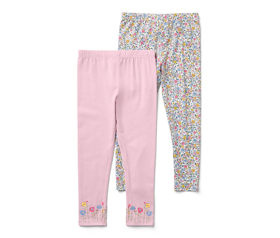 Deux leggings pour enfant : un rose avec des fleurs au bas des jambes, un blanc avec des motifs floraux.