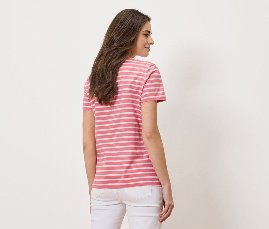 Femme vue de dos, portant un t-shirt rayé rose et blanc et un jean blanc.