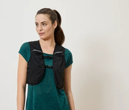 Femme portant un gilet de course noir sur une robe verte.