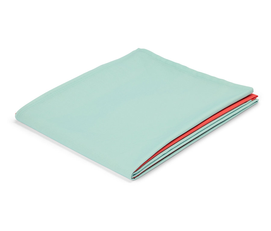 Un tissu menthe plié avec une couche de tissu rouge en dessous repose sur un fond blanc.