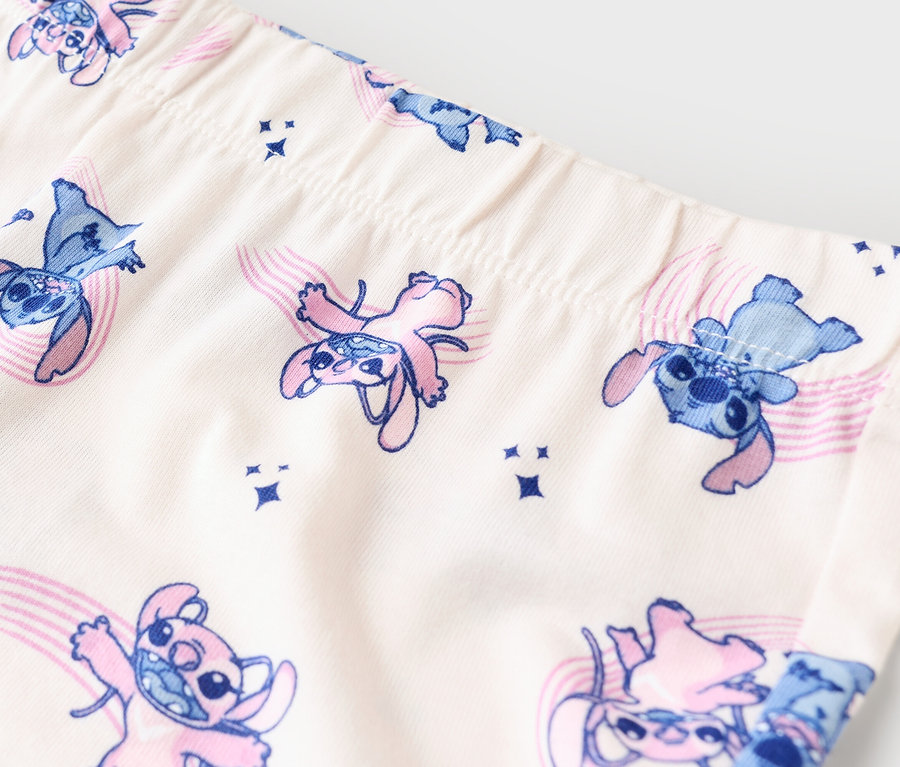Gros plan sur des leggings avec un motif Stitch bleu et rose sur un tissu beige.