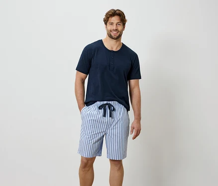 Homme portant un t-shirt bleu et un short rayé.