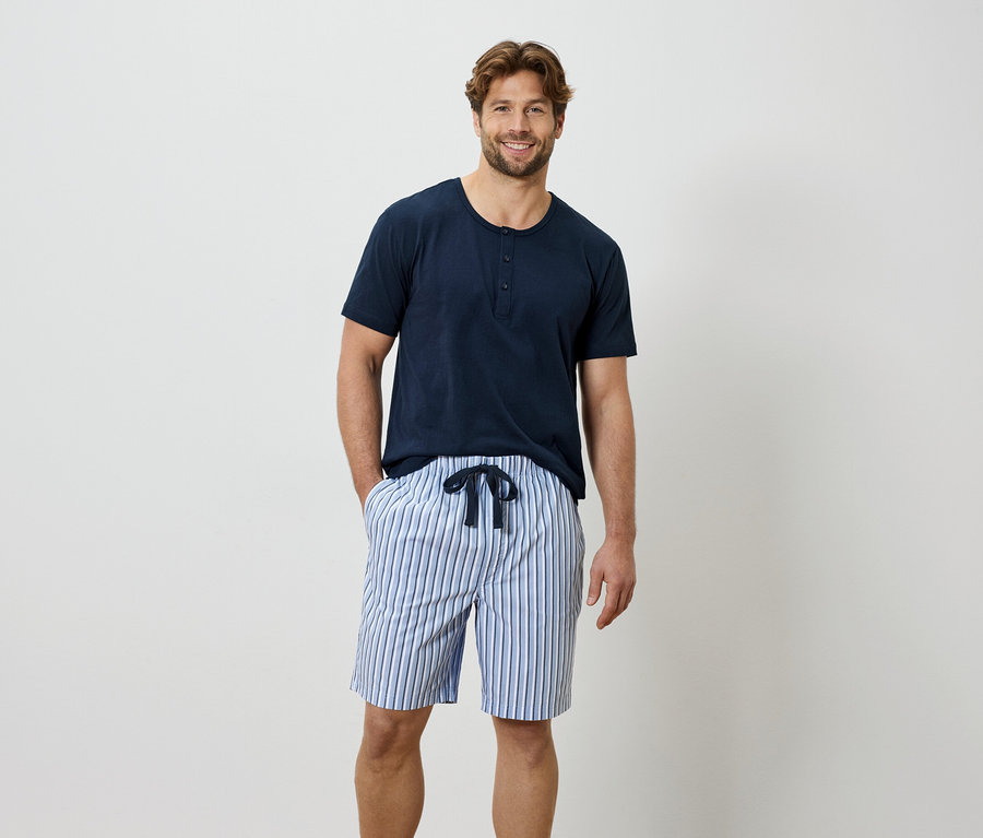 Homme portant un t-shirt bleu et un short rayé.
