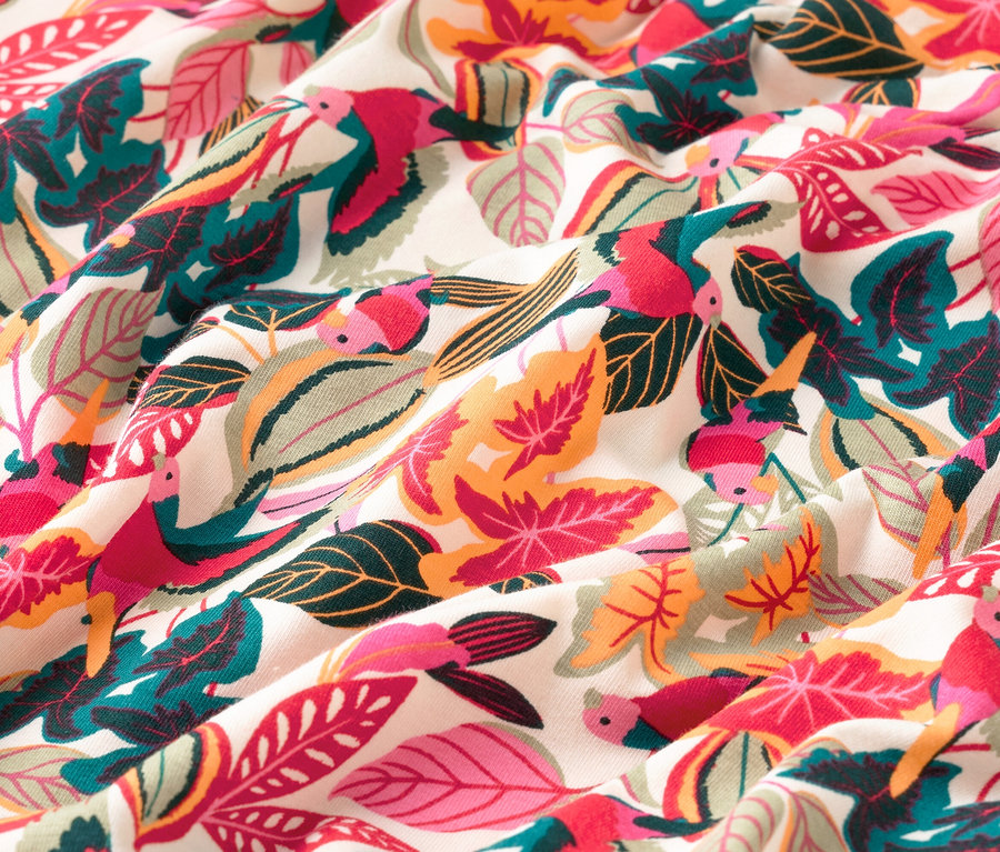 Gros plan d'un tissu à motifs de feuilles et d'oiseaux de différentes couleurs.