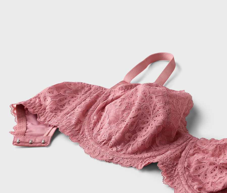 Gros plan d'un soutien-gorge rose en dentelle avec des bretelles sur fond blanc.