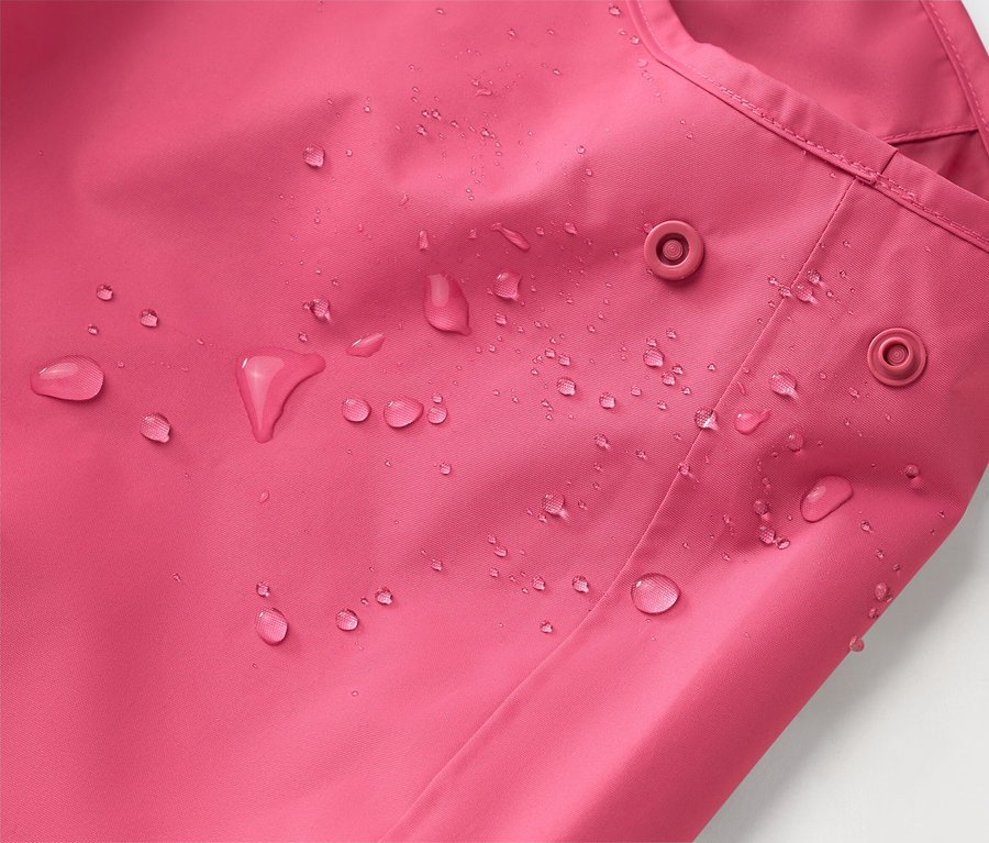 Gros plan d'une veste rose avec des gouttes d'eau et deux boutons-pression.