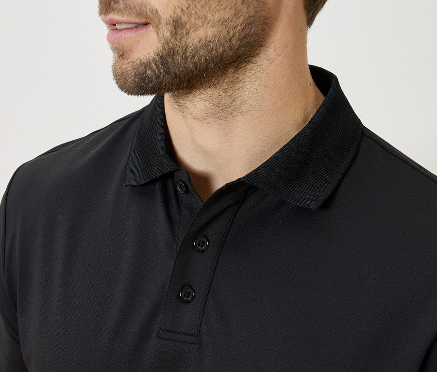 Gros plan sur un homme barbu portant un polo noir.