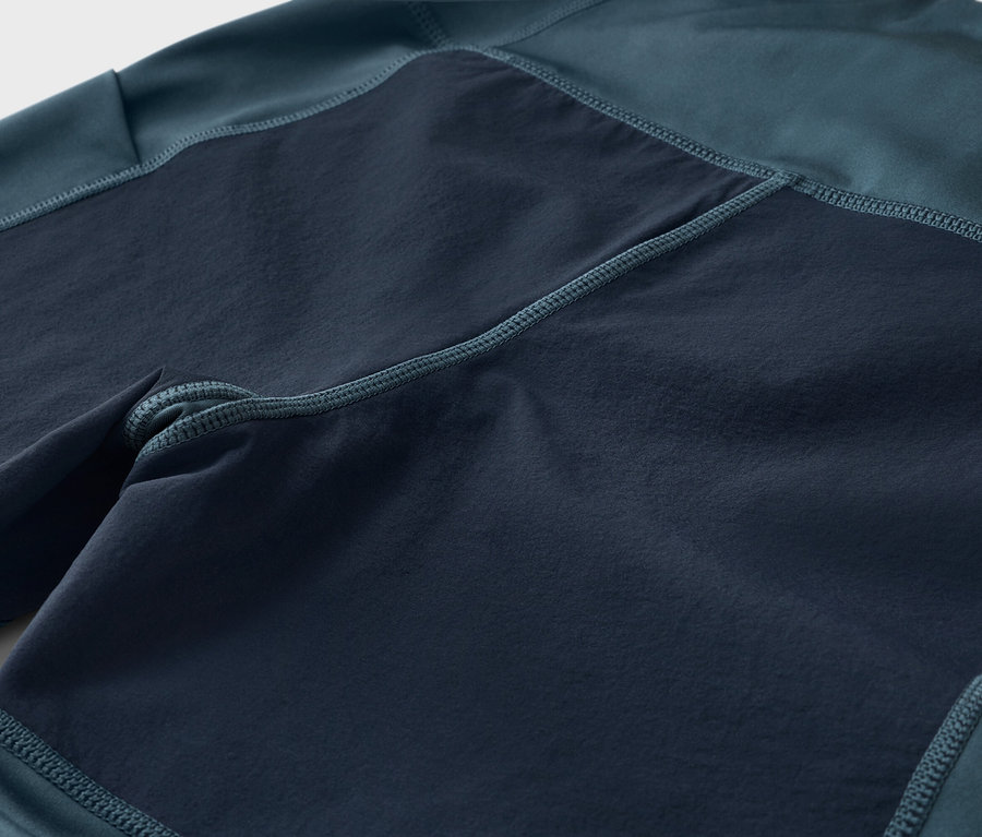 Gros plan d'un pantalon bleu marine et vert avec des empiècements carrés plus foncés.