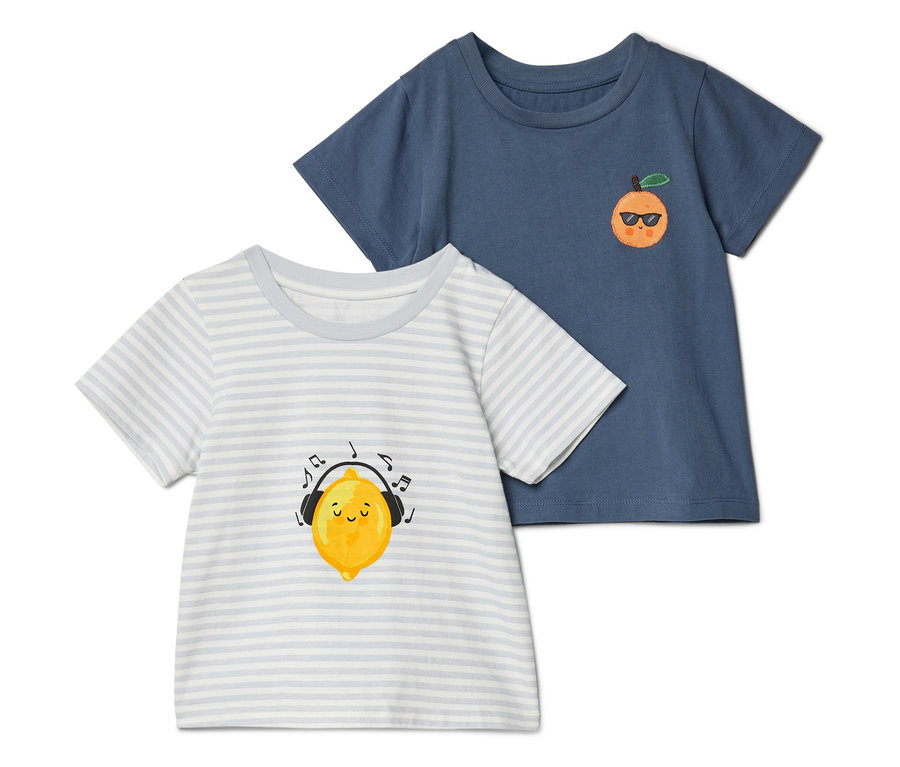 Deux t-shirts sont posés l'un sur l'autre : un bleu avec une orange portant des lunettes de soleil et un rayé avec un citron portant un casque.