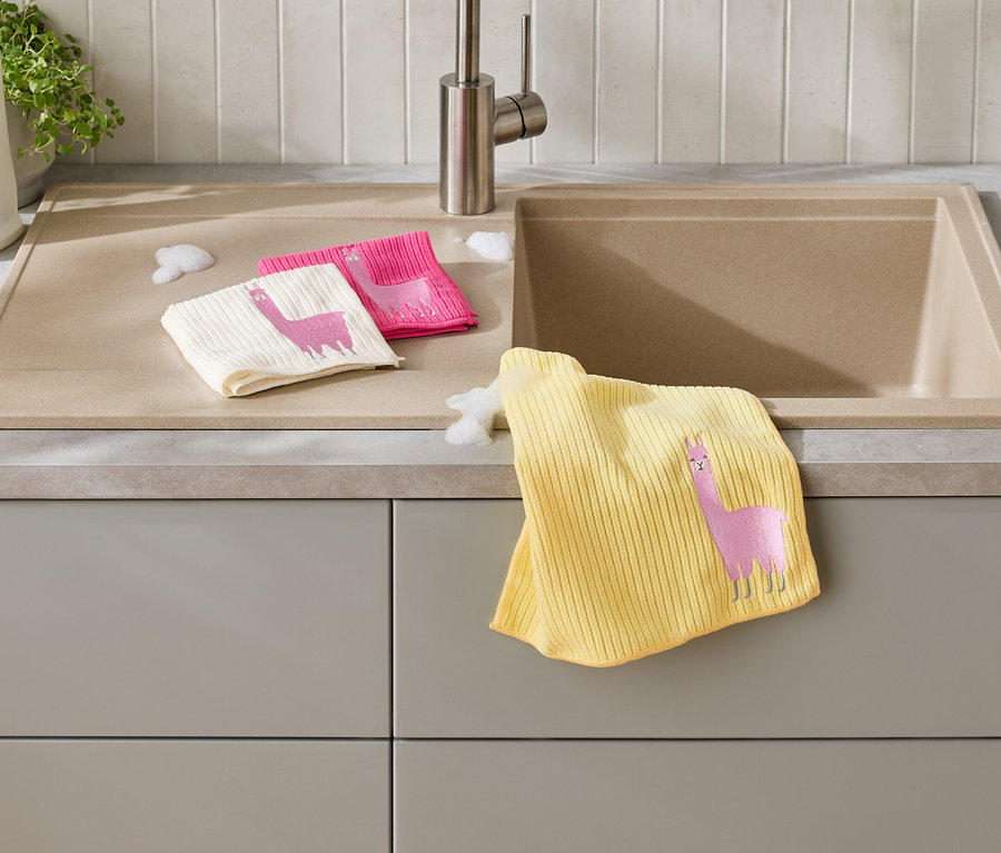 Trois chiffons à vaisselle avec un motif de lama sont posés sur un comptoir de cuisine à côté d'un évier.