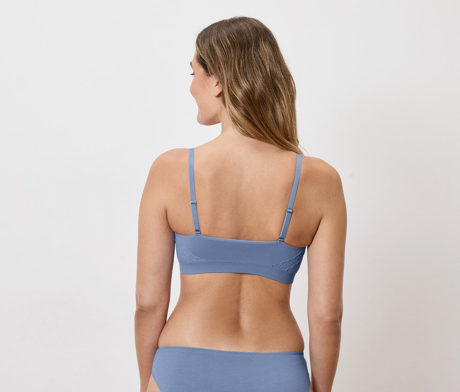 Vue arrière d'une femme aux longs cheveux blonds portant un soutien-gorge et une culotte bleus.