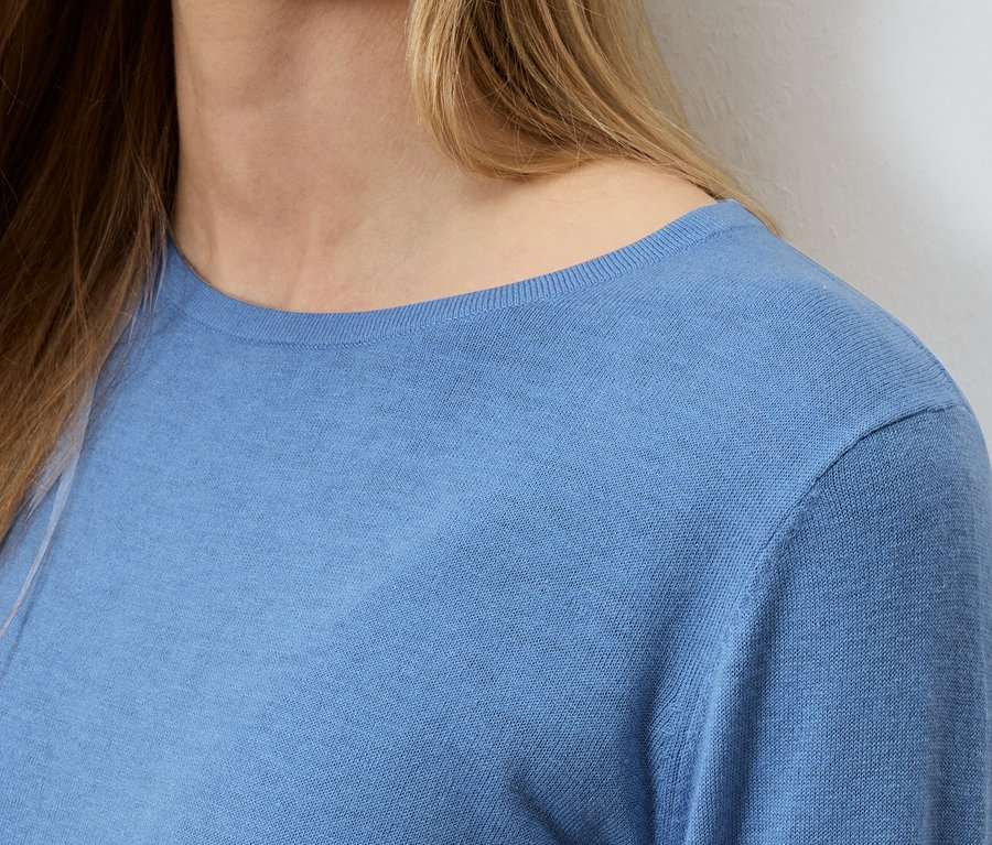 Gros plan d'une femme blonde portant un pull bleu clair.