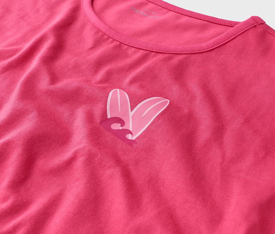 Gros plan d'un t-shirt rose avec un motif de cœur formé de deux planches de surf et d'une vague.