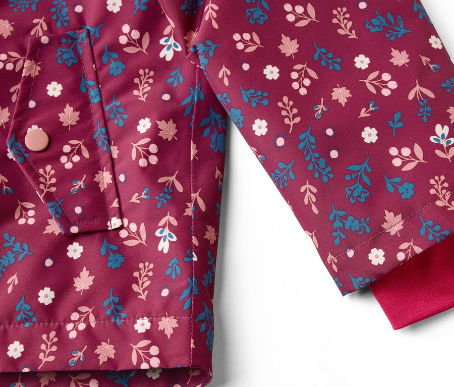 Gros plan sur une veste bordeaux à motifs floraux, une poche et une manche rouge.