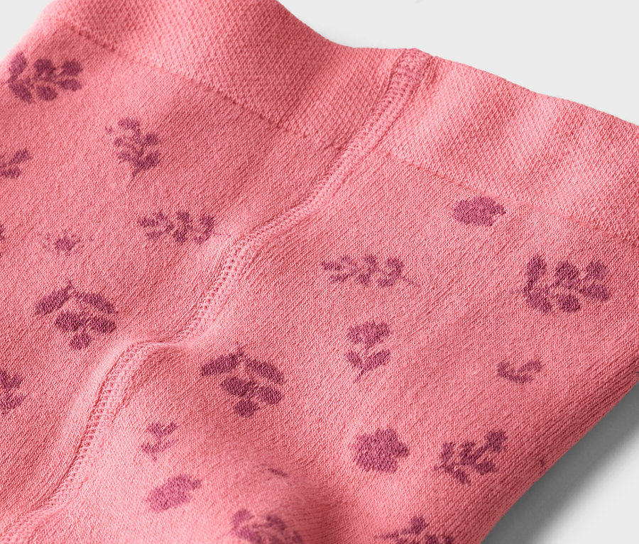 Gros plan sur des collants roses avec un motif floral rose foncé.