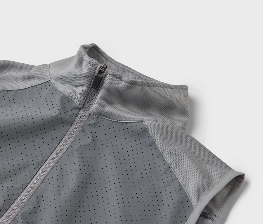 Gros plan d'une veste de sport grise avec fermeture éclair et devant perforé.