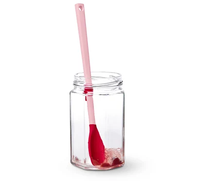 Une spatule rose est posée dans un bocal vide.