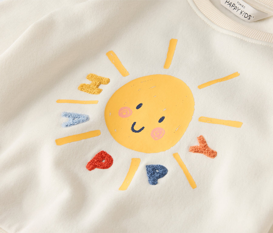 Un sweat-shirt crème avec un soleil souriant et le mot HAPPY.