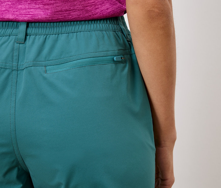 Gros plan sur l'arrière d'un pantalon turquoise avec une taille élastique et une poche zippée.