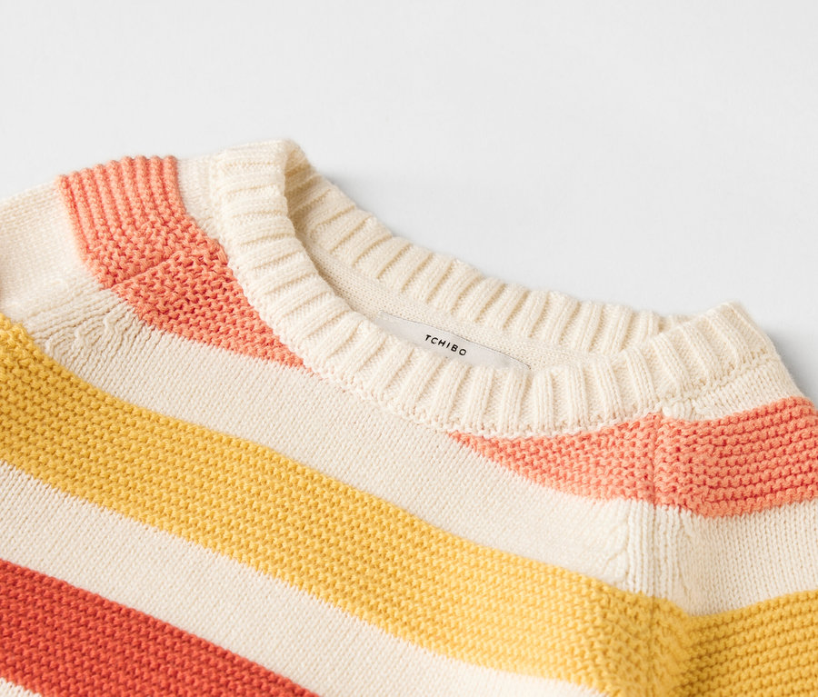 Gros plan d'un pull rayé jaune, rose et beige.