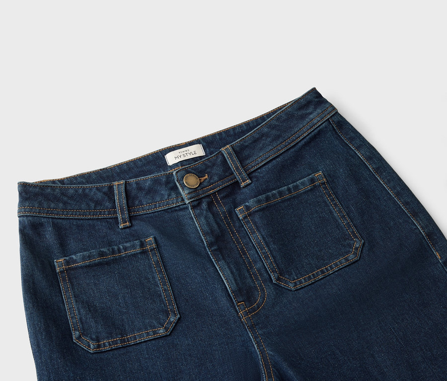 Gros plan d'un jean bleu foncé avec des poches plaquées et des coutures marron clair.