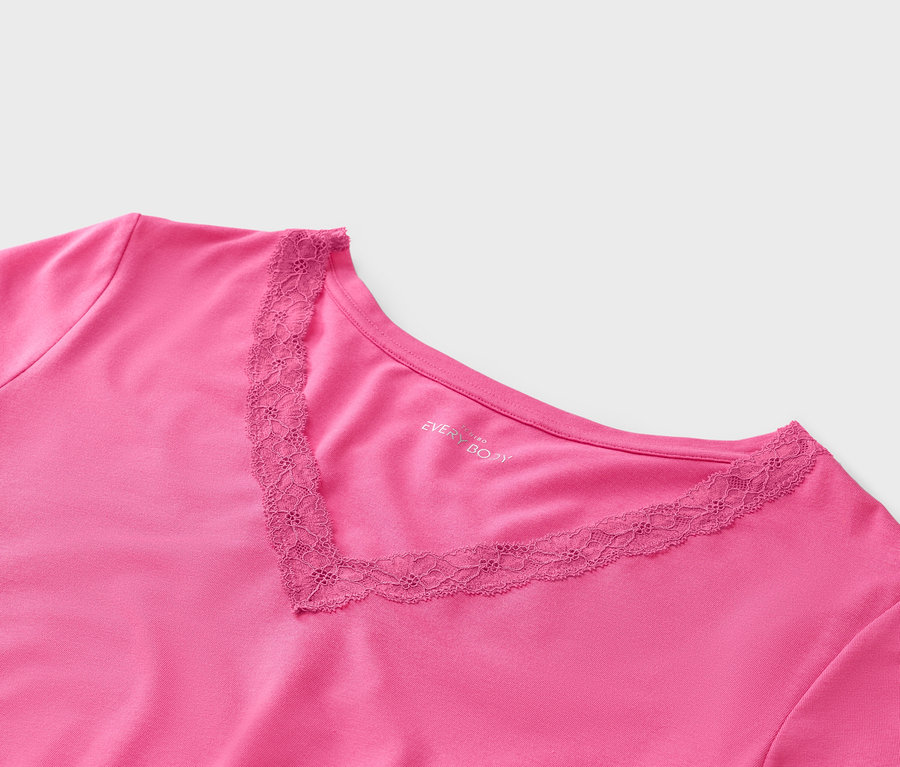 Gros plan sur un t-shirt rose à col en V orné de dentelle.