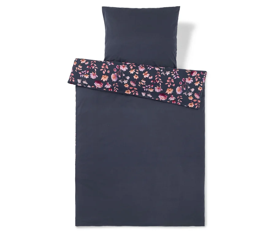 Parure de lit bleu foncé avec une taie d'oreiller. Le haut de la housse de couette est replié, révélant un motif floral de fleurs roses, oranges et violettes avec des feuilles vertes sur un fond sombre.