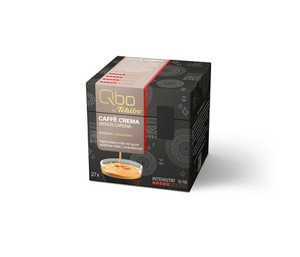 Boîte noire cubique de capsules de café Qbo by Tchibo. La face avant indique le nom du produit 'CAFFÈ CREMA MENOS CAFEÍNA', l'origine 'Brésil | Colombie' et la description 'Harmonieusement doux avec une note légèrement sucrée | décaféiné'. Sont également mentionnés '27x' et 'INTENSITÉ 5/10'. Une image montre du café dans une tasse.
