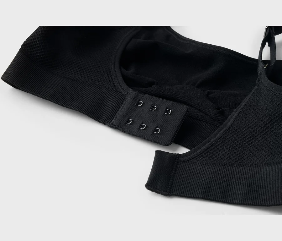 Gros plan d'un soutien-gorge noir avec une fermeture à agrafes au dos, montrant des détails de tissu côtelé et texturé.